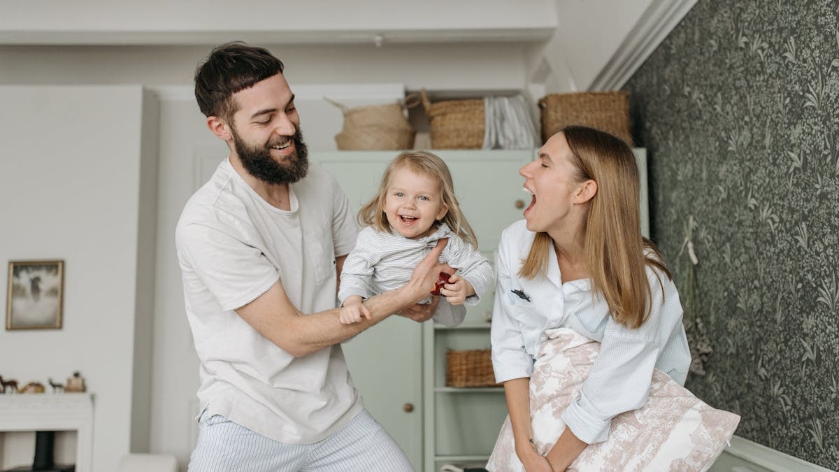 Joyful parents playing with their daughter at home, showcasing love and happiness.